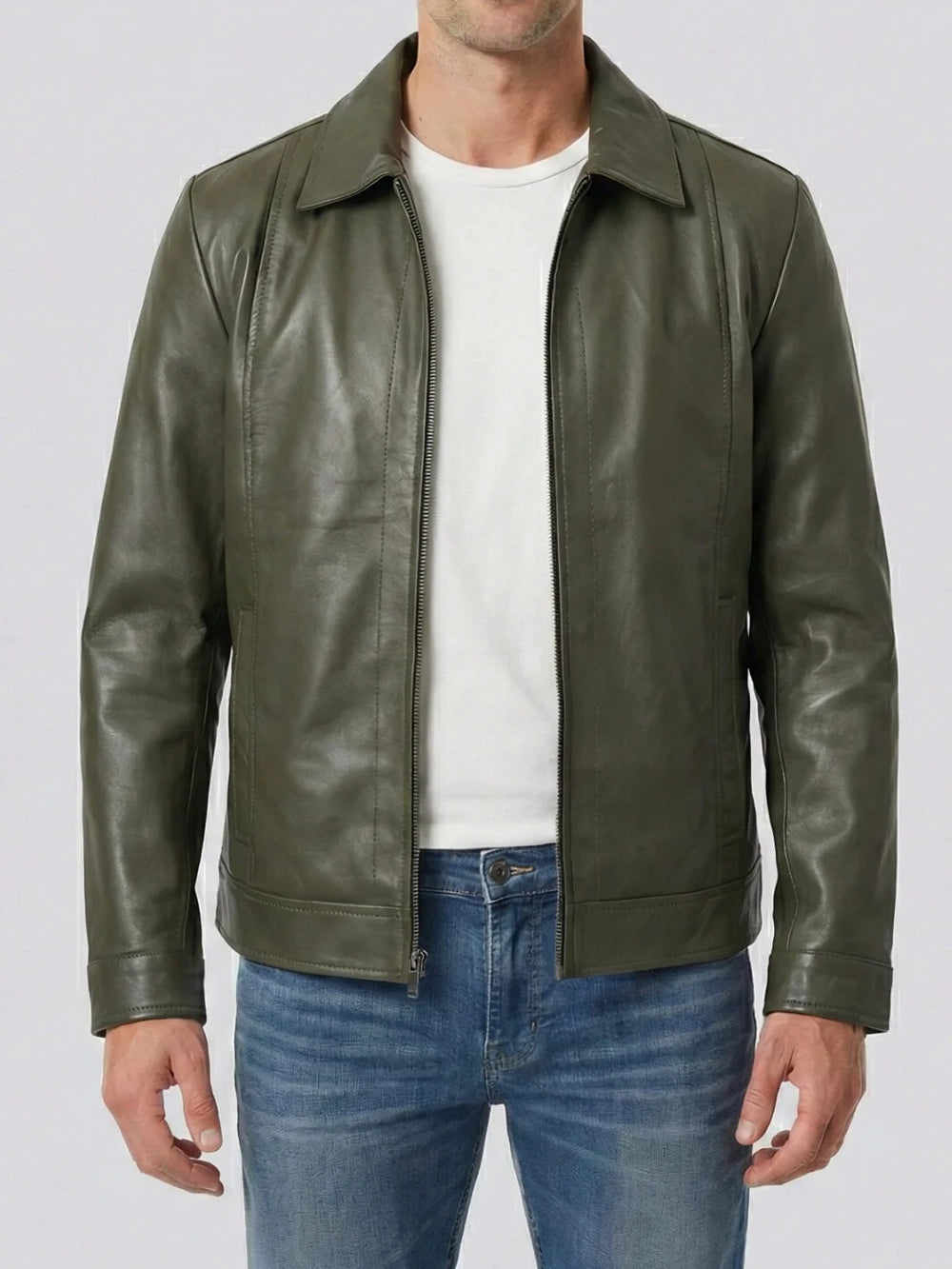 Man wearing a green leather jacket over a white shirt and blue jeans on a light gray background